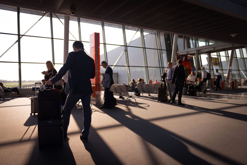 Essential Travel Tips for First-Time International Travelers at the Airport traveler at an international airport holding a passport, boarding pass, and rolling suitcase while looking at the departure information board.